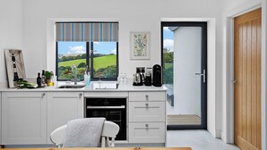 A modern kitchen with a large window, a coffee machine, and a view of the countryside. - Spacious Luxury Retreat with parking & views (Kingswear)