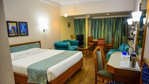 Habitación de hotel con cama, escritorio y silla, una mesita y un sofá.