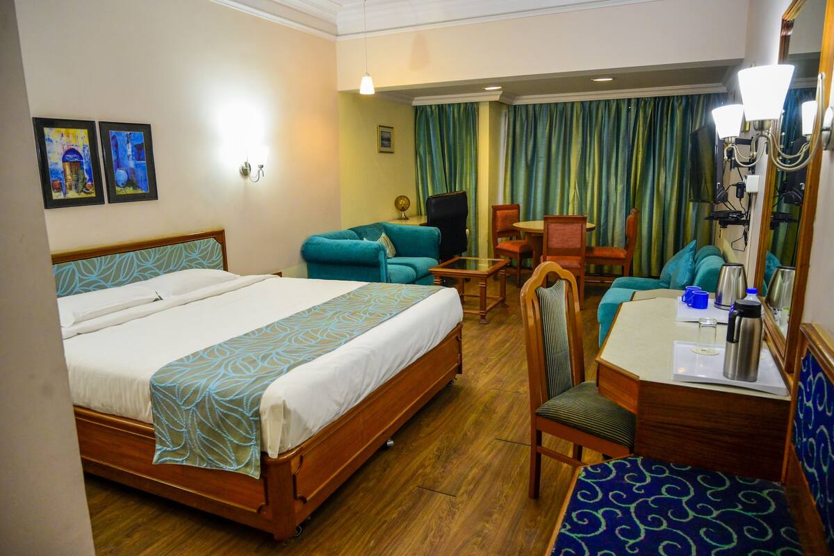 A hotel room with a bed, a desk with a chair, a small table, and a sofa.