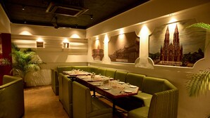 Un restaurante con asientos de color verde, una larga mesa dispuesta para comer y carteles de la iglesia de Santa Filomena en la pared.