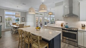 A modern kitchen with a large island, stainless steel appliances, and pendant lighting.