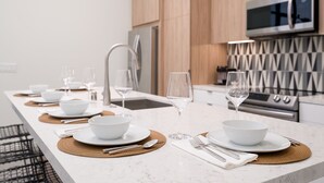 A modern kitchen with a long island, stainless steel appliances, and a microwave above the counter. - Historic Post Office Loft w/firepit near Zoo (San Diego)