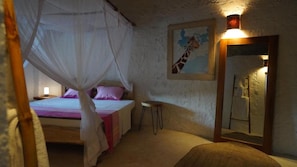 A room with a bed under a canopy, a small stool, a painting of a giraffe, and a mirror. - The Mida Creek (Watamu)