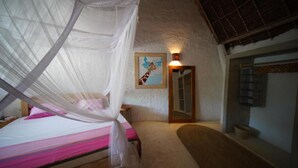 A bedroom with a bed under a canopy, a small stool, a painting of a giraffe, and a wooden door. - The Mida Creek (Watamu)