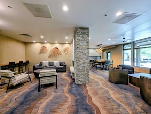 A hotel lobby with a stone pillar, a sofa, chairs, a dining area, and a large window. - Walk to Gondola, River Run, Hot Tubs + Garage (Keystone)