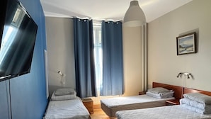 A hotel room with two single beds, a TV, a painting, and a window with curtains. - Carlstad Hostel Sport (Karlstad)