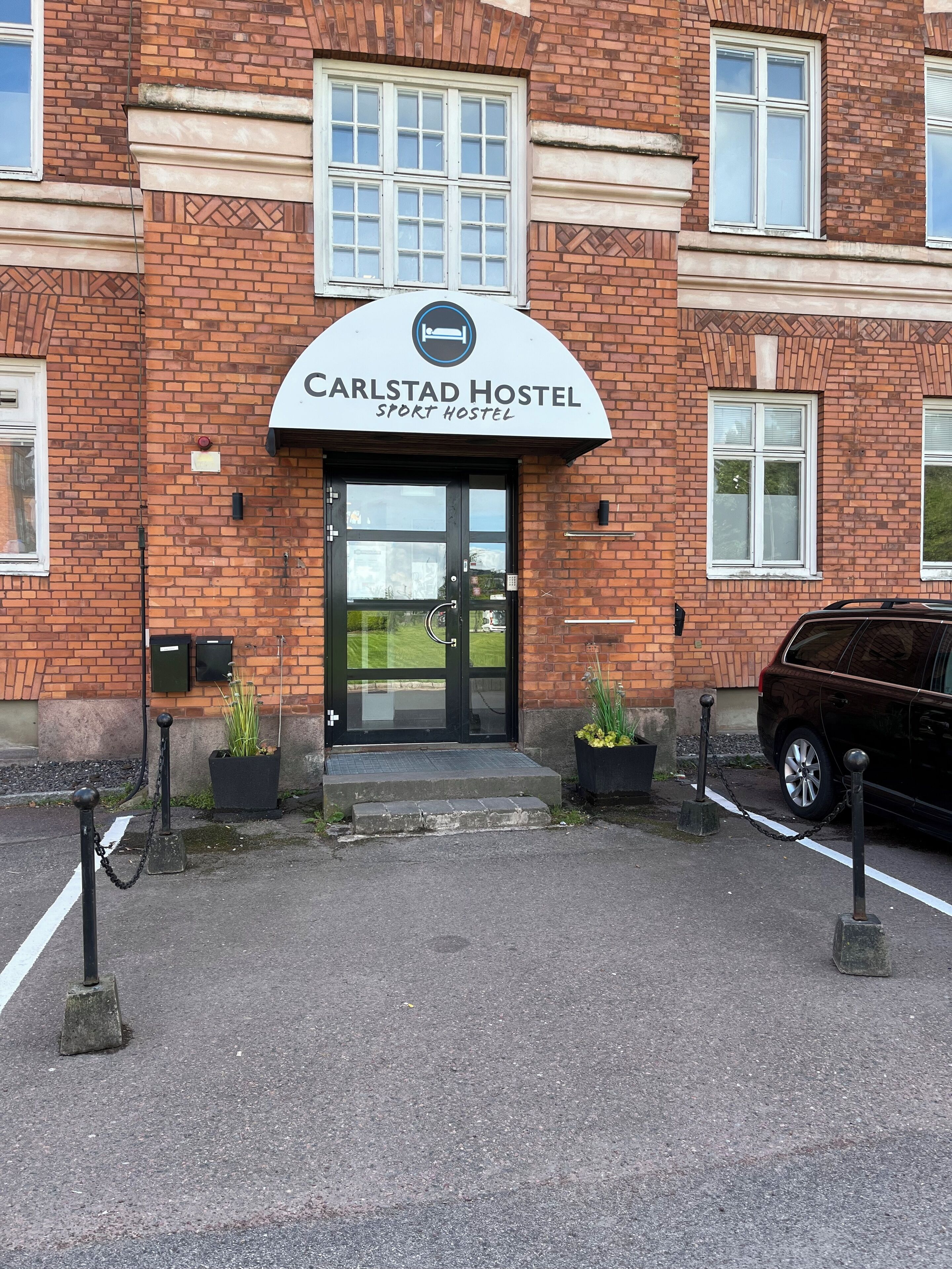 A brick building with a sign reading "Carlstad Hostel Sport Hostel".