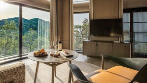 A modern living room with a large window, a round table with food and drinks, a sofa, and a TV. - Yanbai Villa, Beijing (Huairou)