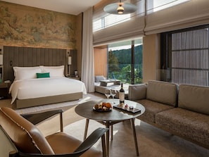A modern hotel room with a large bed, a sofa, a dining table, and a view of the outdoors. - Yanbai Villa, Beijing (Huairou)
