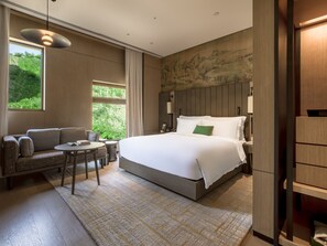 A modern hotel room with a large bed, a sofa, a small table, and a view of greenery through the window. - Yanbai Villa, Beijing (Huairou)