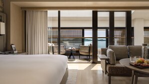A hotel room with a large bed, a dining table with fruit, a sofa, and a view of the sea through floor-to-ceiling windows. - Yanbai Villa, Beijing (Huairou)