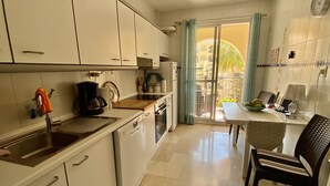 Eine Küche mit weißen Schränken, einer Kaffeemaschine und einem Essbereich mit Tisch und Stühlen.