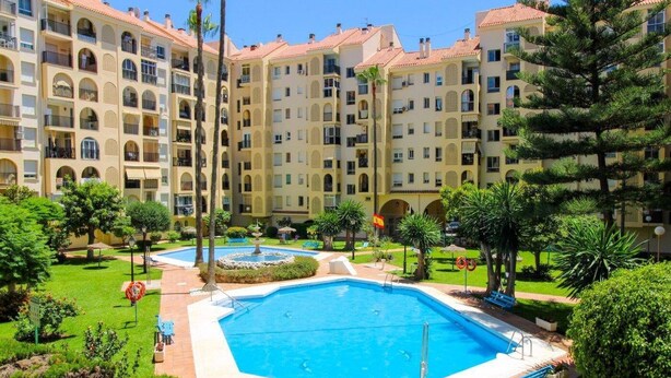 Ein Hotelinnenhof mit einem zentral gelegenen Pool, umgeben von üppiger Bepflanzung und einem mehrstöckigen Gebäude mit Balkonen.