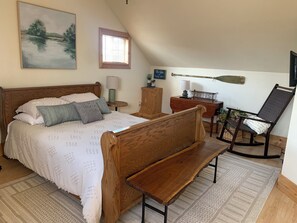 Ein Schlafzimmer mit einem hölzernen Bett, einer Bank, einem Schreibtisch und einem Schaukelstuhl.