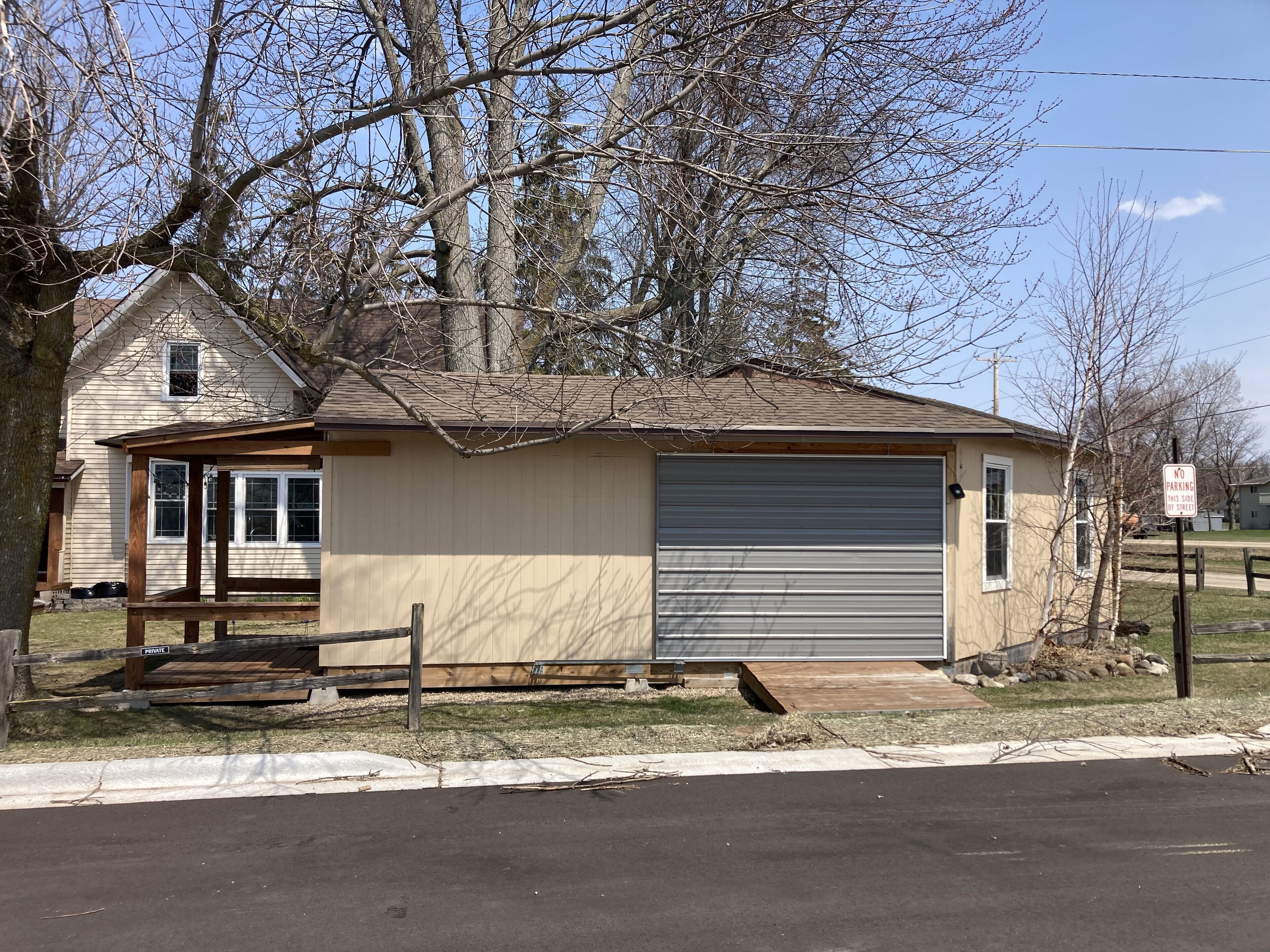 A single-story building with a closed garage door, a small porch, and a 'NO PARKING' sign.