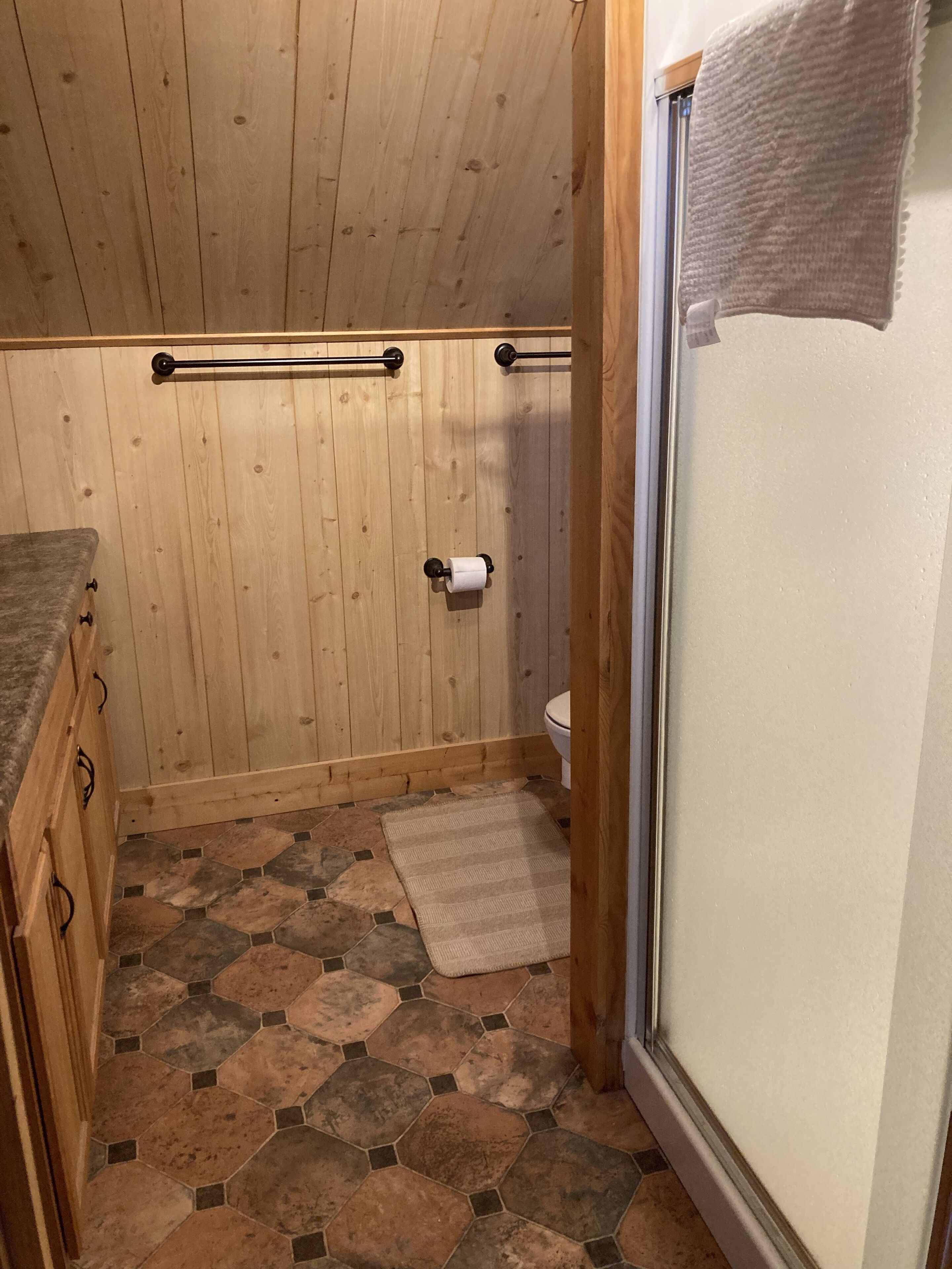 Un baño con paneles de madera, un inodoro, un perchero y una zona de ducha.