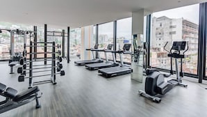 A modern gym with treadmills, weight machines, and a squat rack.