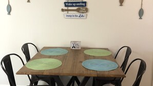 Une table à manger avec quatre chaises, une décoration murale en bois ornée de phrases motivantes et un petit panneau fixé au mur.