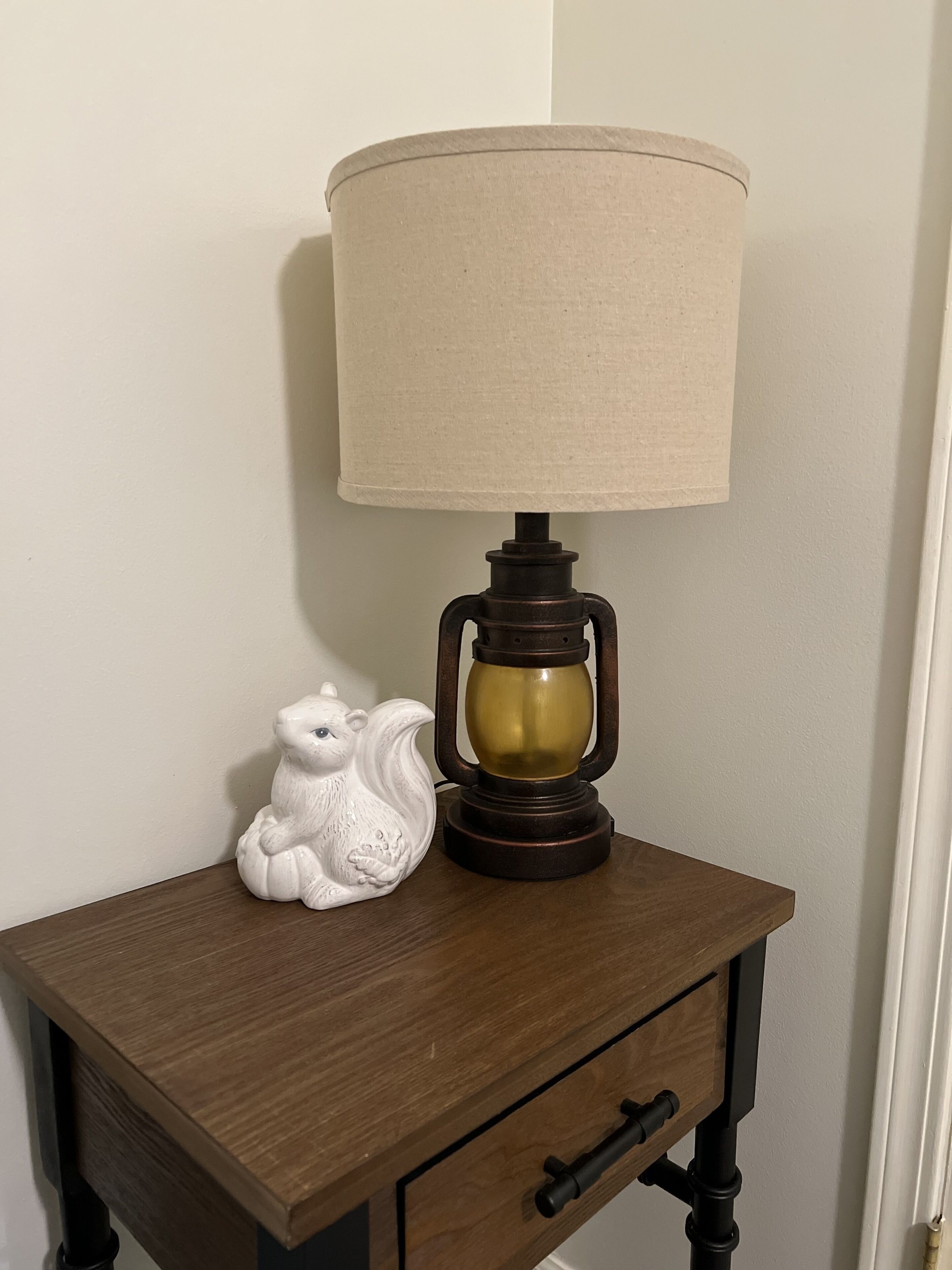A wooden nightstand with a lamp and a ceramic frog figurine.