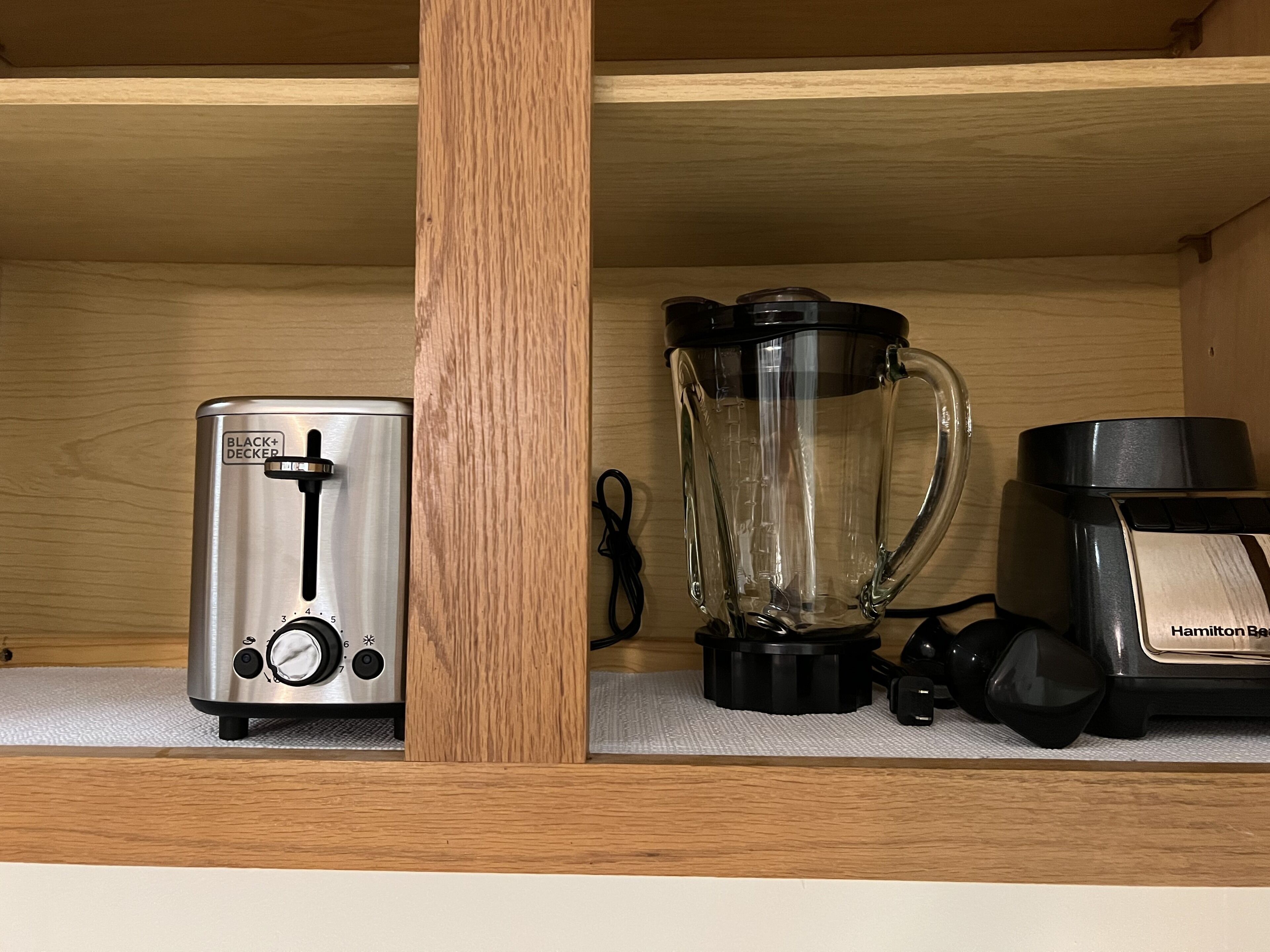 A kitchen shelf with a toaster, a blender, and a coffee maker.