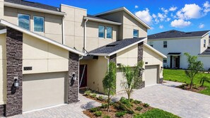 A modern two-story house with a garage, stone accents, and a well-maintained front yard.