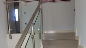 Una escalera con barandillas de vidrio y peldaños color beige.