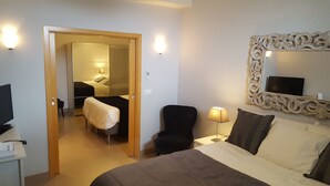 Una habitación de hotel con una cama, una silla, un escritorio y un televisor.