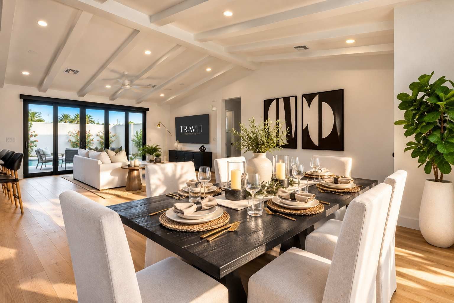 Un coin repas avec une table en bois foncé, dressée pour six personnes, entourée de chaises blanches.