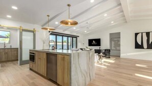 A modern kitchen with a marble island, wooden cabinets, and pendant lighting. - The Kingsley|Custom|Heated Pool|Chef Kitchen|Chess (Scottsdale)