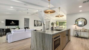 A modern kitchen with a marble island, wooden cabinets, and pendant lighting. - The Kingsley|Custom|Heated Pool|Chef Kitchen|Chess (Scottsdale)