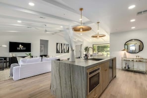A modern kitchen with a marble island, wooden cabinets, and pendant lighting. - The Kingsley|Custom|Heated Pool|Chef Kitchen|Chess (Scottsdale)