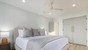 A modern bedroom with a large bed, a ceiling fan, and a wardrobe.