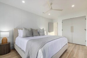 A modern bedroom with a large bed, a ceiling fan, and a wardrobe.