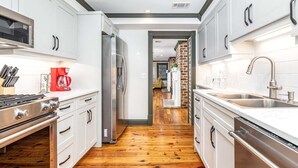 Una cocina moderna con armarios blancos, electrodomésticos de acero inoxidable y suelo de madera.