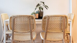 A dining area with four wicker chairs and a table, a potted plant, and a wall with a crack.