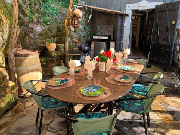 Un espace de restauration en plein air avec une table ronde prévue pour quatre personnes, entourée de chaises dotées de sièges rembourrés.