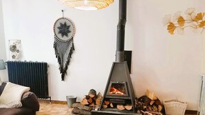 Un salon chaleureux avec un poêle à bois, un attrape-rêves et un grand luminaire en fibres tressées.