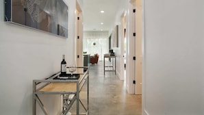 A hallway with a dining area, a table with a bottle and glasses, and a painting on the wall. - The Garden District's Pied-à-Terre on Prytania | 4 Bedrooms (New Orleans)