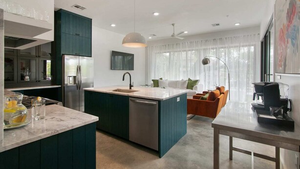 A modern kitchen with a central island, built-in appliances, and a dining area with a table and chairs. - The Garden District's Pied-à-Terre on Prytania | 4 Bedrooms (New Orleans)