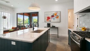 A modern kitchen with a central island, a dining area with a sofa, and a large window offering a view. - The Garden District's Pied-à-Terre on Prytania | 4 Bedrooms (New Orleans)