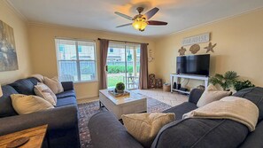 A living room with a ceiling fan, a TV, and a sign that says 'PARADISE.'