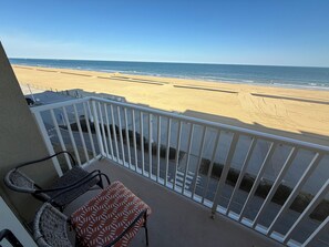 A balcony with a view of the beach, a chair, and a small table. - Dolphin Beach condo with indoor pool, ocean views, steps to the beach (Virginia Beach)