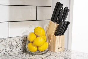 Un recipiente de vidrio con limones sobre una encimera de cocina, junto a un bloque de cuchillos.