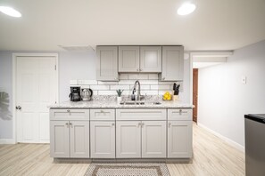 Una cocina moderna con armarios blancos, encimera de granito y lavamanos integrado.