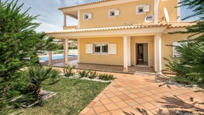 A two-story house with a tiled patio, a swimming pool, and a garden with pine trees. - Villa Das Oliveiras, Large grounds, walk to Marina (Albufeira)