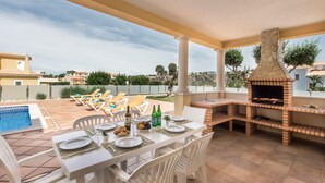 An outdoor dining area with a pool, lounge chairs, and a stone-built barbecue grill. - Villa Das Oliveiras, Large grounds, walk to Marina (Albufeira)