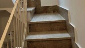 Una scala con ringhiere in legno e una piccola finestra in cima.