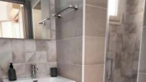 Un bagno moderno con un mobile lavabo grigio, uno specchio e uno spazio doccia.