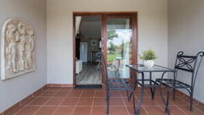 A patio with a glass door leading to a kitchen, a small table with chairs, and a potted plant. - Three Thymes Inn (Pretoria)