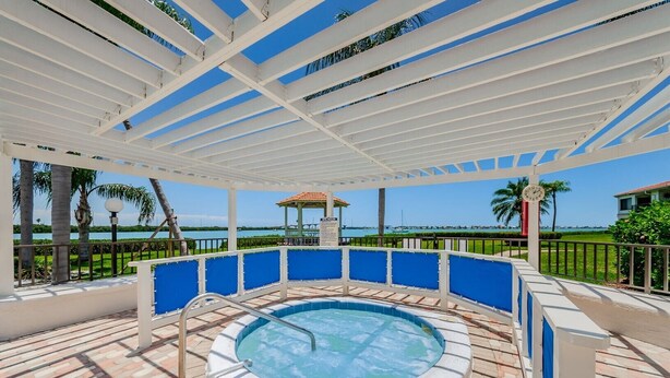 Ein Whirlpool mit Blick auf das Meer, umgeben von einer weißen Pergola und blauen Geländern.